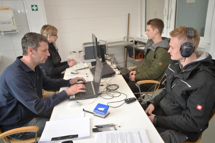 Die Auszubildenden Kevin Lemping und Maximillian Hantel nehmen am Hörtest teil, den Matthias Selchow und Margrit Lehnen, beide Arbeitsmedizinische Assistenten der BG Bau, durchführen.