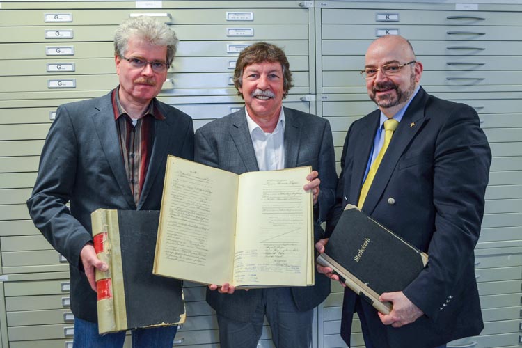 Oldenburgs Stadtarchivar Claus Ahrens mit Wolfgang Grams und Nikolai Donitzky von Ancestry zeigen einen von über 500 Bänden, die digitalisiert worden sind.