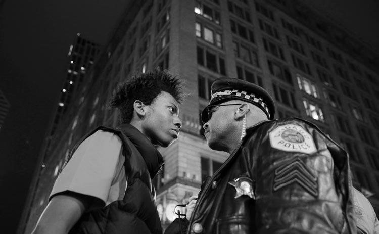 Der junge Demonstrant Lamon Reccord und ein Polizei-Sergeant stehen sich während einer Demonstration gegen rassistische Gewalt in den USA direkt gegenüber. Die Proteste hatten sich an der Veröffentlichung eines Videos entzündet, das zeigte, wie der 17-jährige Laquan McDonald von einem Chicagoer Polizisten erschossen wurde. Foto: John J. Kim, USA Der junge Demonstrant Lamon Reccord und ein Polizei-Sergeant stehen sich während einer Demonstration gegen rassistische Gewalt in den USA direkt gegenüber.