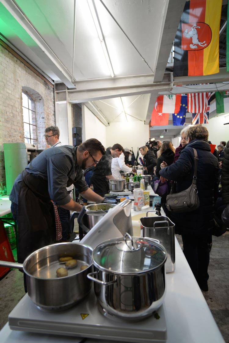 An einer langen Tischreihe wurde in der Oldenburger bau_werk Halle in drei Durchgängen gekocht.