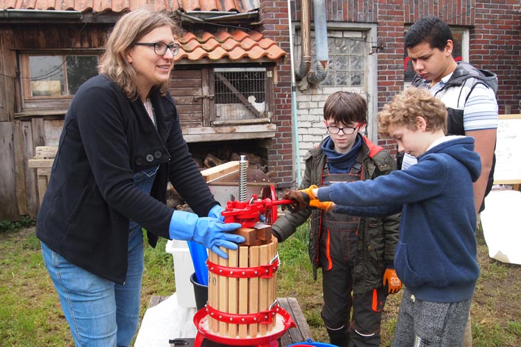 Antje Bruns-Osolin mit Schülern an der kleinen Saftpresse.