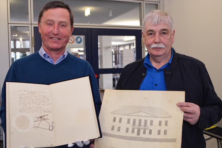 Dr. Wolfgang Henninger und Dr. Matthias Nistal (von links) zeigen das Original der ersten Verfassung  des Staatsgrundgesetzes von 1849 sowie eine Originalzeichnung des einstigen Landtages und heutigen Standesamtes in Oldenburg am Pferdemarkt.