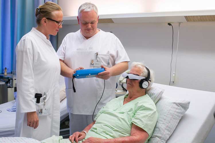 Dr. Ulrike Raap und Matthias Wilke legen die Einstellungen am sogenannten Media-Center der Videobrille fest – die Patientin kann über eine Fernbedienung die Inhalte der ablenkenden Filme steuern.