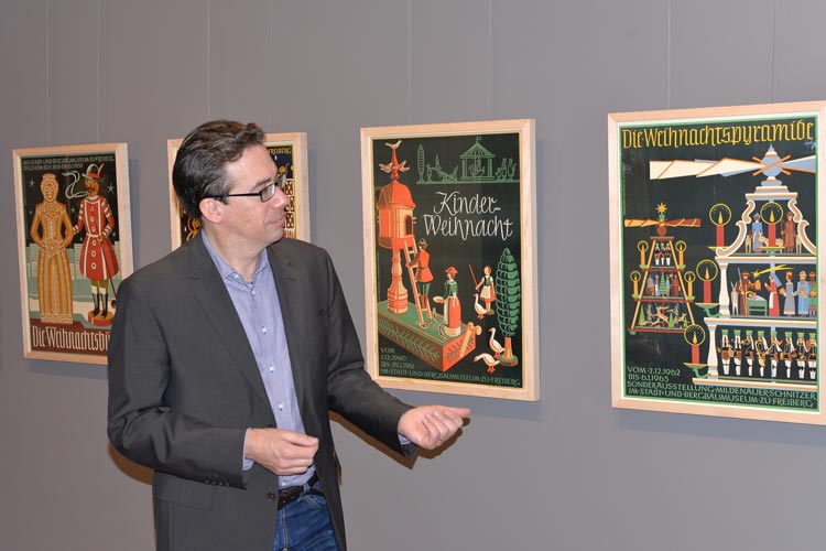 Provenienzforscher Dr. Marcus Kenzler zeigt in der Kabinettschau im Prinzenpalais am Damm Weihnachtsplakate der 1950er und 1960er Jahre aus West- und Ostdeutschland.