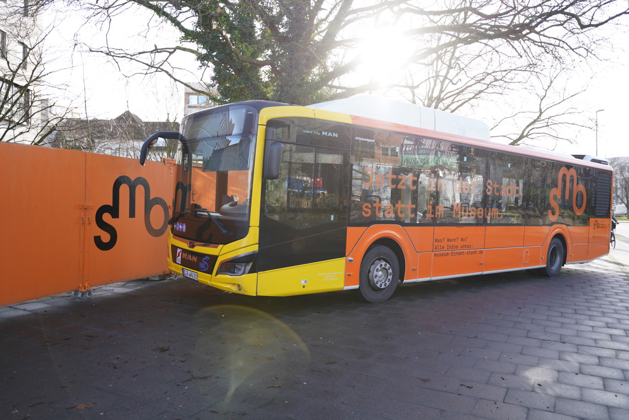 Der orangefarbener Linienbus wirbt während der Schließungszeit für Stadtmuseumsprojekte.