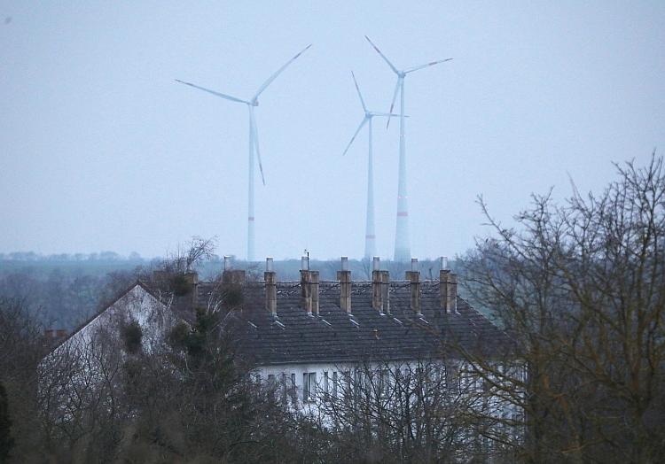 Ein Mehrfamilienhaus mit Windrädern im Hintergrund (Archiv), via dts Nachrichtenagentur