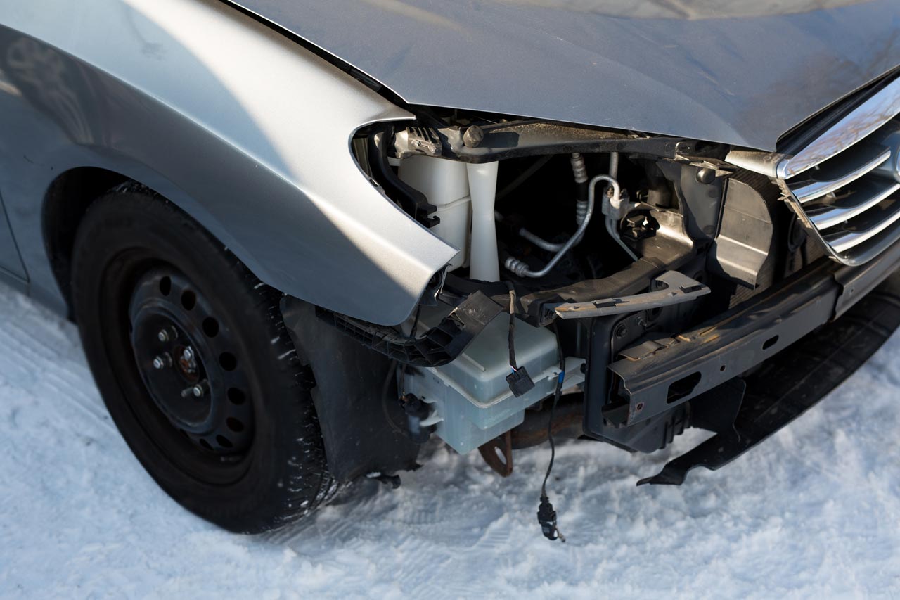 Silberne Fahrzeug mit Unfallschaden vorne rechts, Vorderreifen und Stoßstange stark beschädigt.